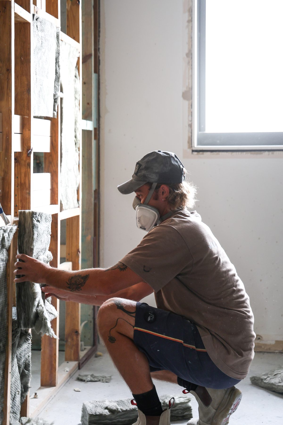 A Jace Space tradesperson installing insulation in a wall frame on site